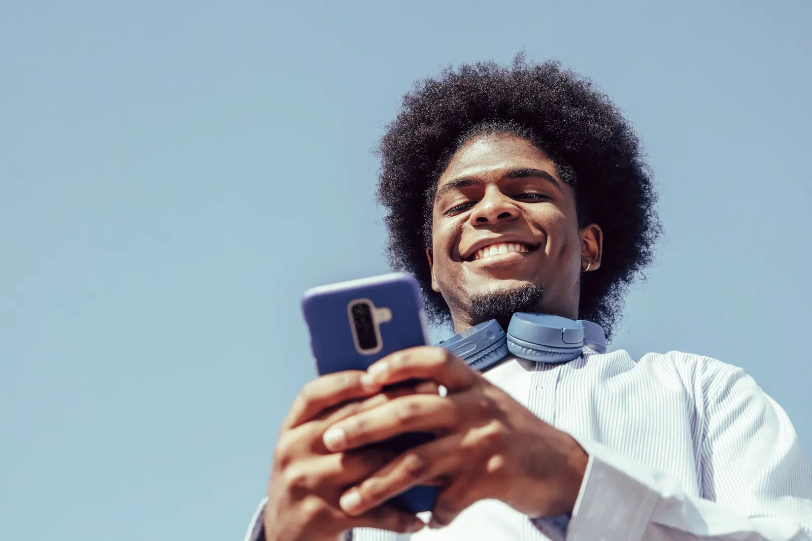 Un homme au Cameroun consulte son téléphone en souriant après avoir reçu un transfert.